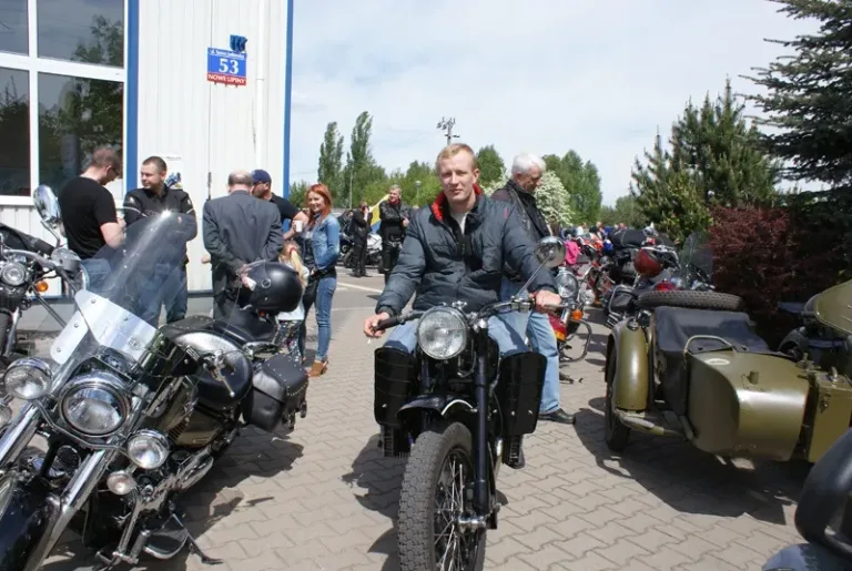 Motocyklista na zabytkowym motocyklu z koszem przed stacją kontroli pojazdów